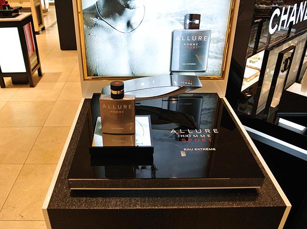 Allure Parfum-Flasche steht auf einem Display aus Acrylglas in schwarz mit Dekoelementen
