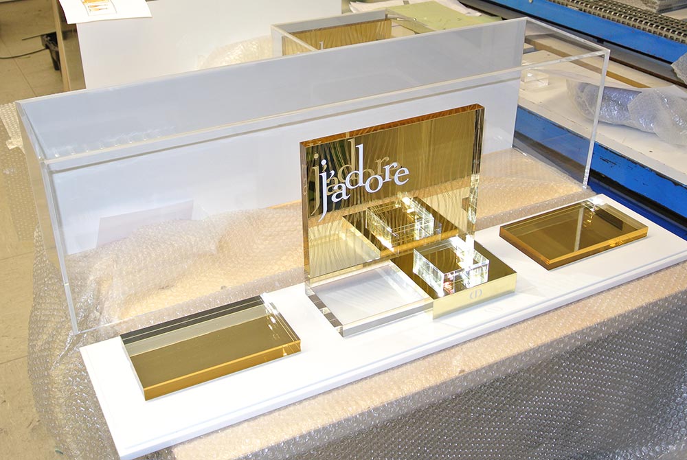 Warendisplay aus Acrylglas mit goldenen, weißen und farblosen Elementen für Produkte von j´adore