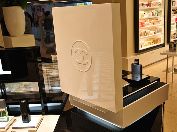 Rückansicht eines Displays aus Acrylglas mit Logo von Chanel auf dem eine Parfum-Flasche steht