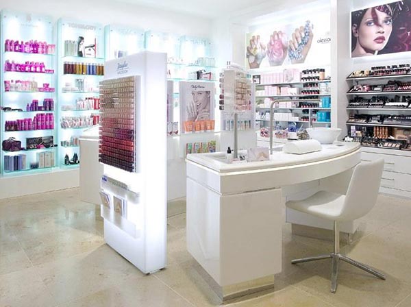 Ladeneinrichtung eines Geschäfts für Kosmetikartikel mit beleuchteten Regalen und Displays aus Acryglas sowie einem Tisch für die Nagelpflege