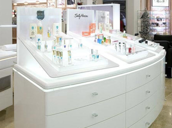 Weiße Kommode aus Acrylglas mit integrierten und beleuchteten Produktdisplays mit Kosmetikartikeln