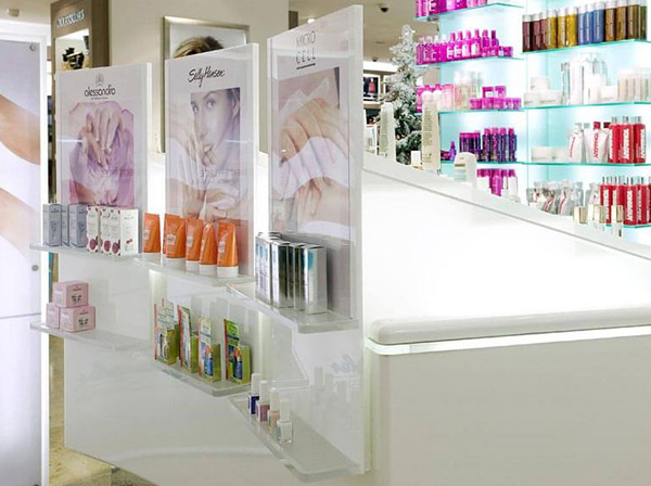 Produktdisplays aus weißem und farblos transparentem Acyrlglas, auf denen Kosmetikartikel stehen, montiert an ein Sideboard