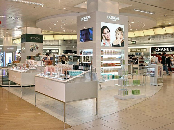 Ladeneinrichtung eines Geschäfts für Kosmetikartikel von L`Oréal mit beleuchteten Tischen, Produktdisplays und Regalen