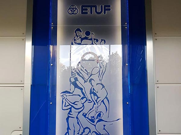 Wandbild aus Acrylglas, blauer Hintergrund und matt-weißem Vordergrund. Abgebildet sind verschiedene Sportler und das Logo der ETUF